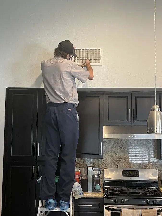 Technician inspecting an air vent during HVAC service in Cullowhee